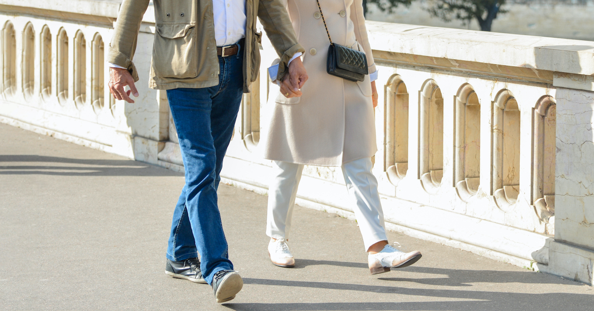 Couple seen from the waist down holding hands and walking across a bridge in Europe