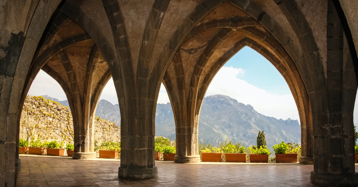 View through a series of stone archways out toward mountains and green plants of the Villa Cimbrone Gardens
