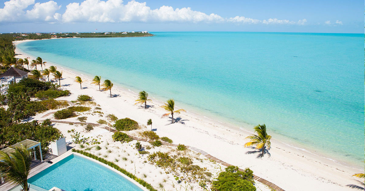 Aerial view of a white sand beach with light blue water